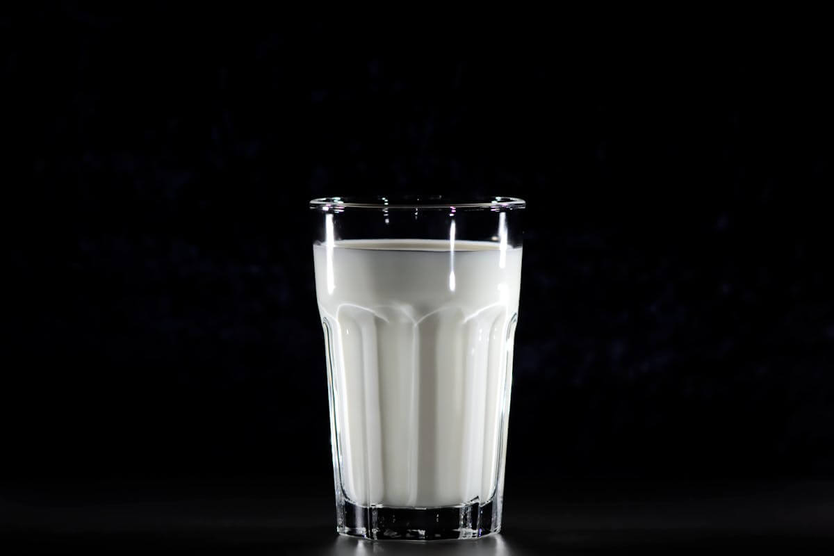 milk in a clear glass cup, with black background